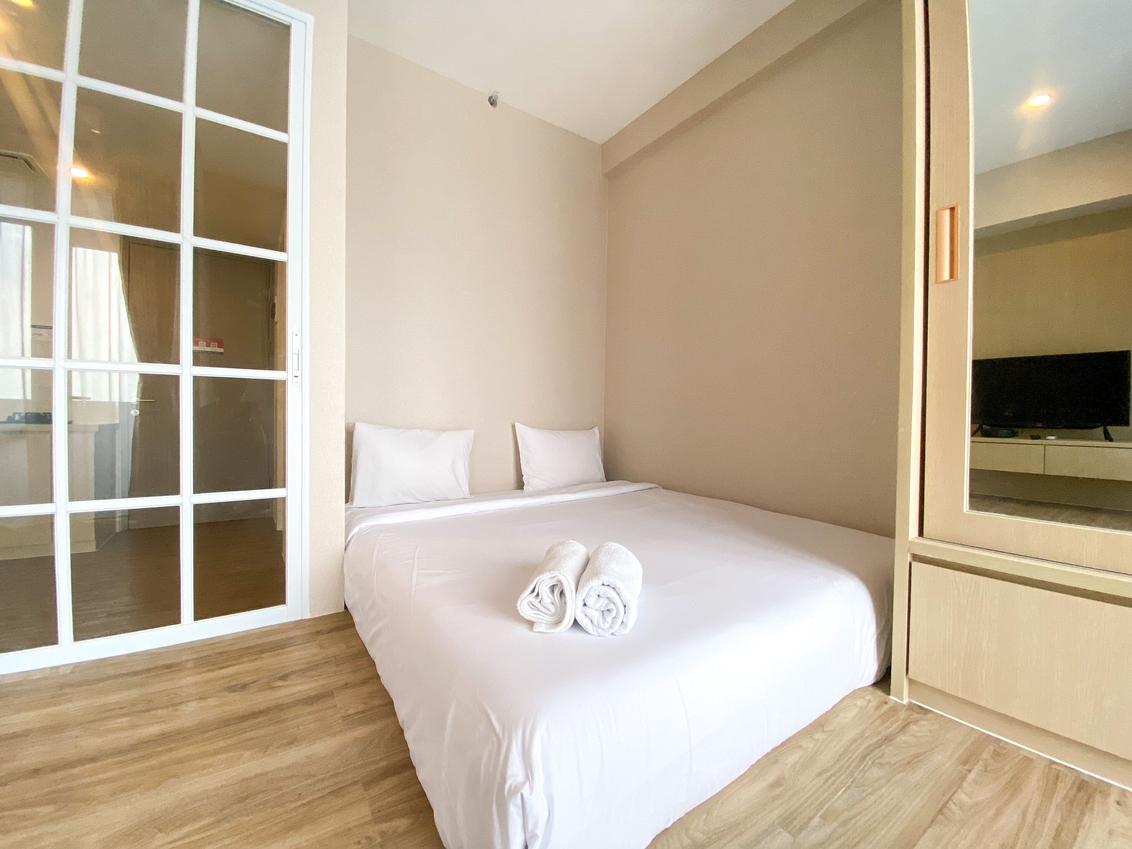 A hotel room with a large bed, a TV, and a sliding glass door leading to a balcony.
