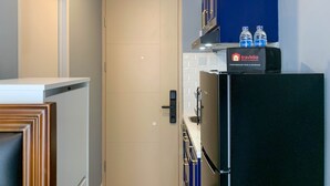 A compact kitchen with a refrigerator, a water dispenser, and a trash bin. - Cozy Studio At 31Th Floor Tokyo Riverside Pik 2 Apartment (Teluknaga)