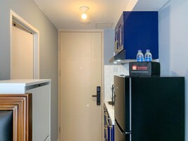Una cocina compacta con refrigerador, dispensador de agua y basurero.
