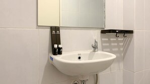 A bathroom with a white sink, a mirror, and toiletries. - Cozy Studio At 31Th Floor Tokyo Riverside Pik 2 Apartment (Teluknaga)