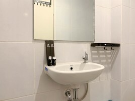 A bathroom with a white sink, a mirror, and toiletries.