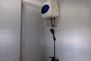 Enjoy a refreshing shower in this room, featuring a convenient showerhead and mounted water heater.