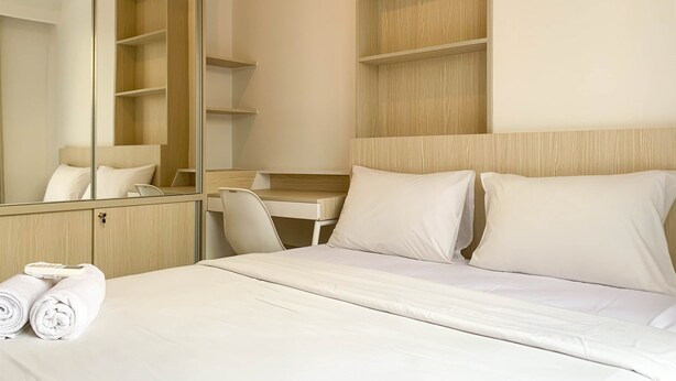 Una habitación de hotel con cama, escritorio, silla, armario y espejo.