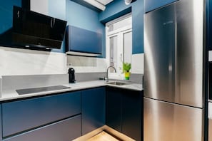 A modern kitchen with dark blue cabinets, a stainless steel refrigerator, and a built-in oven. - Elegancia y Calma by Wehomes (Santander)