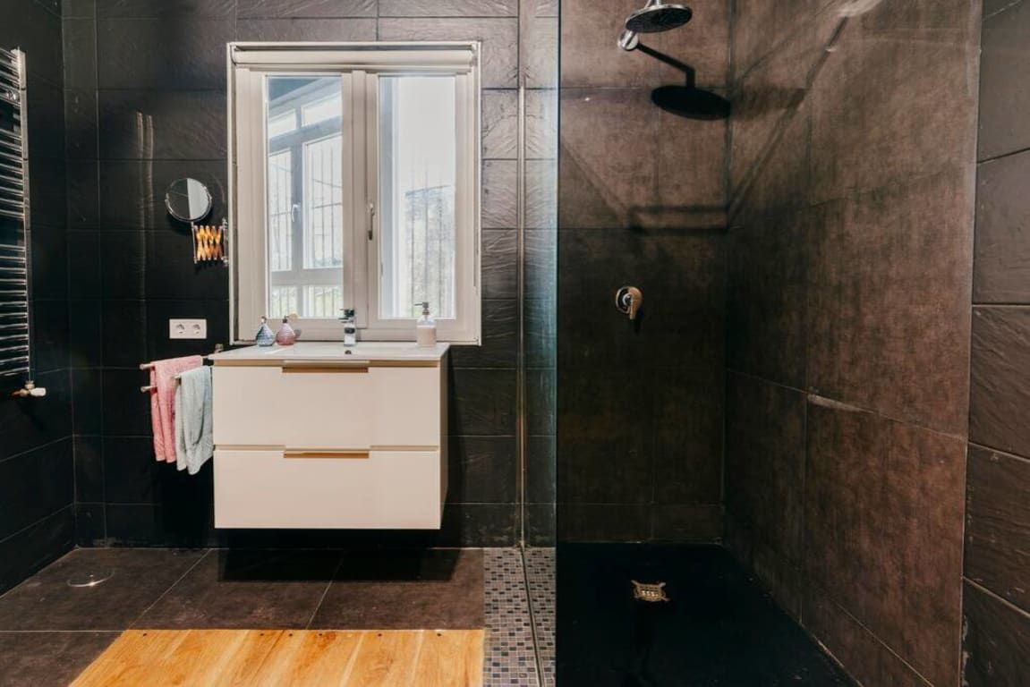 A modern bathroom with a white vanity, a mirror, and a shower area.