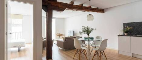 A modern living space with a dining area, kitchen, and a visible balcony.