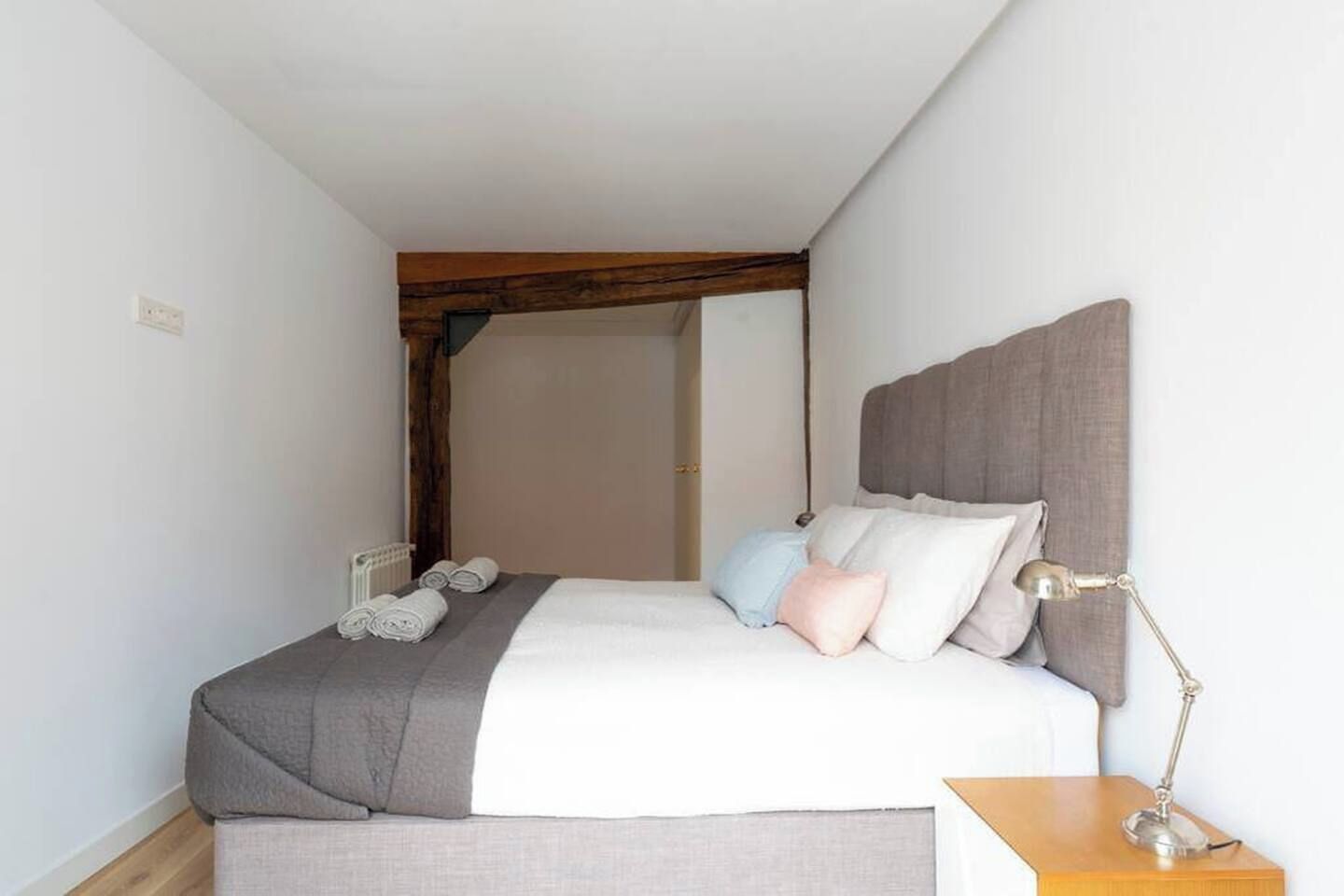 A bedroom with a bed, pillows, a bedside lamp, and a radiator.