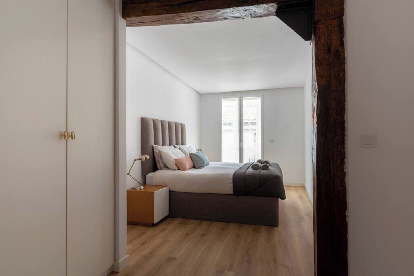 A bedroom with a bed, bedside table, and a window.
