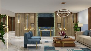 Un salon moderne doté d’un grand téléviseur à écran plat, de fauteuils bleus à revêtement en tissu, d’une table basse en bois et d’un tapis à motifs.