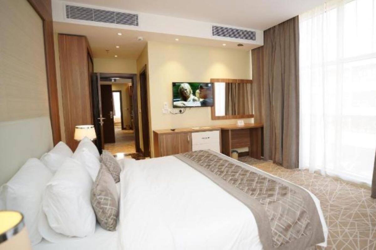 Quarto de hotel com uma cama grande, uma escrivaninha, uma televisão e vista para o exterior.