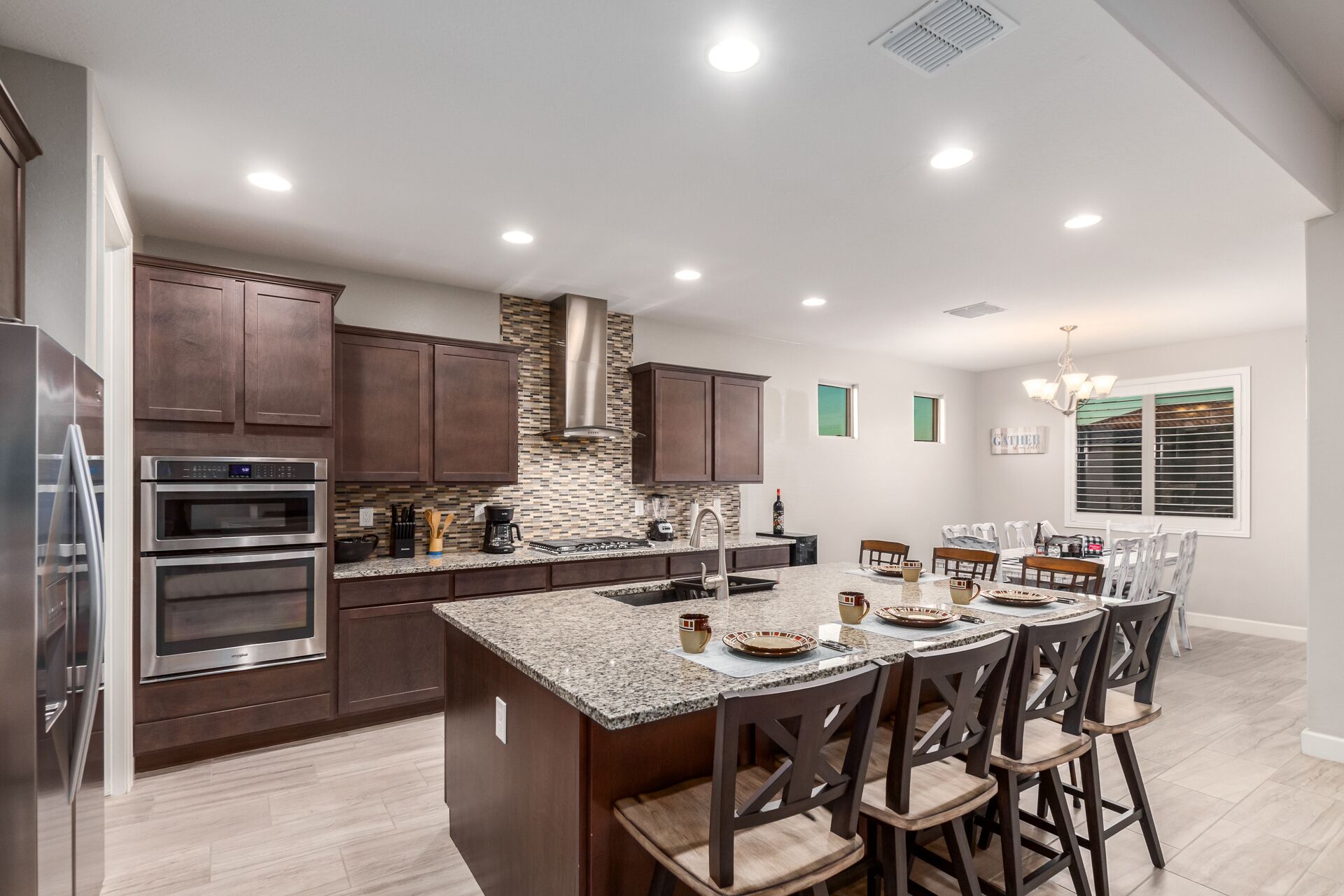 A modern kitchen with granite countertops, stainless steel appliances, and a central island with bar stools.