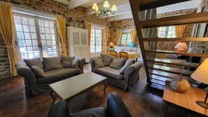 A cozy living area with stone walls, a wooden staircase, and a dining table with chairs.