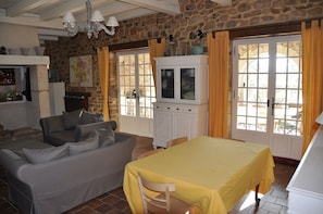 A room with a stone wall, a sofa, a bed with a yellow bedspread, a cabinet, and a window with curtains. - PROVENCAL VILLA. 1Ha ABSOLUTE COMFORT & QUIETNESS. Swimming pool 10x5 WI-FI (fiber) (GOUDARGUES)