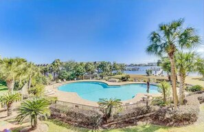A pool surrounded by palm trees and a clear blue sky. - Pirates Point of View Top Floor! (Fort Walton Beach)