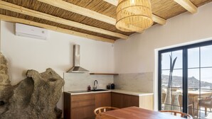 Eine moderne Küche mit Holzbalken, einer Steinwand und Blick durch große Fenster.