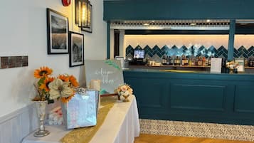 Zona de bar con mostrador azul verdoso, una televisión y un panel decorativo con diseño de rombos.