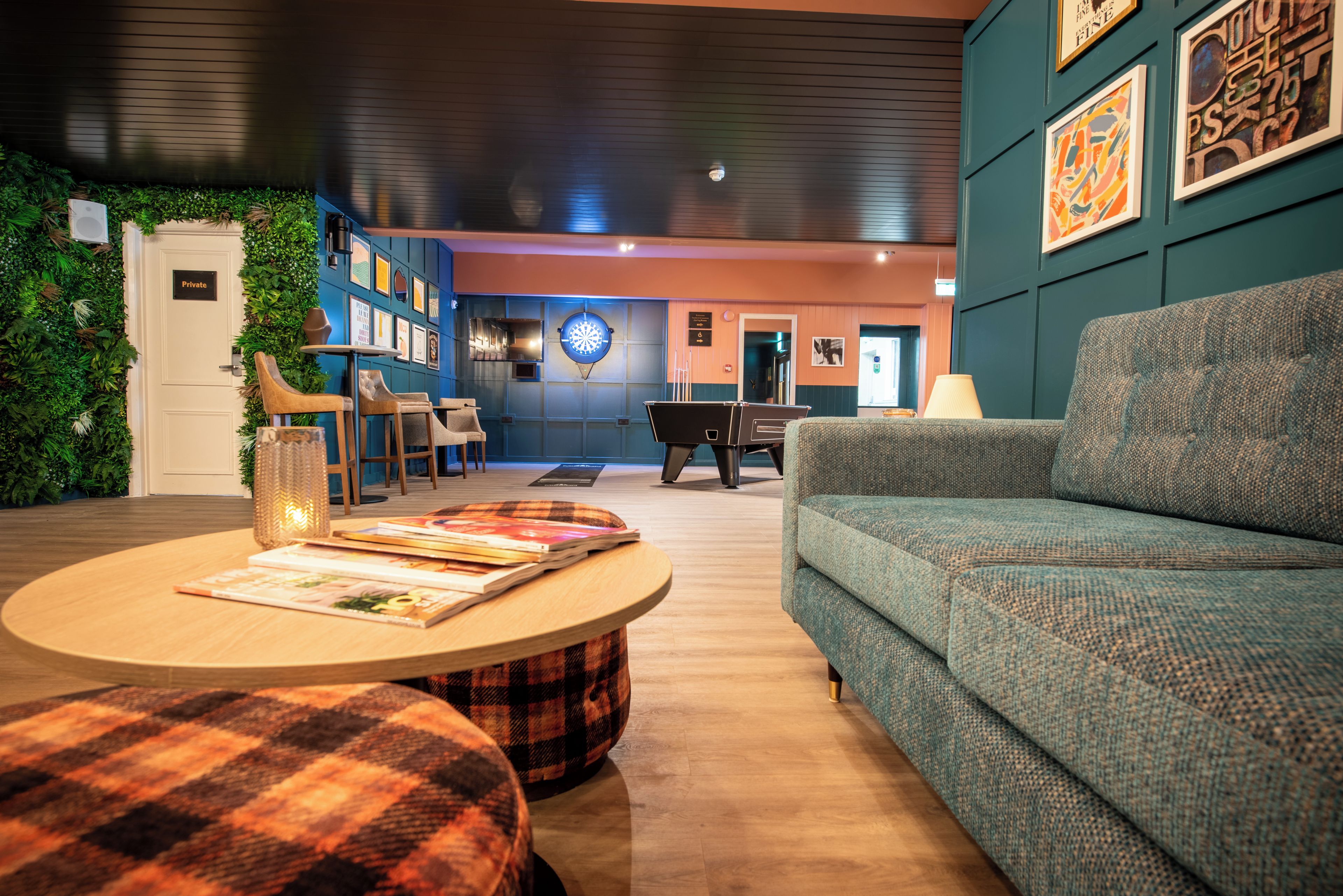 A cozy lounge area with a sofa, a coffee table, and a dartboard.