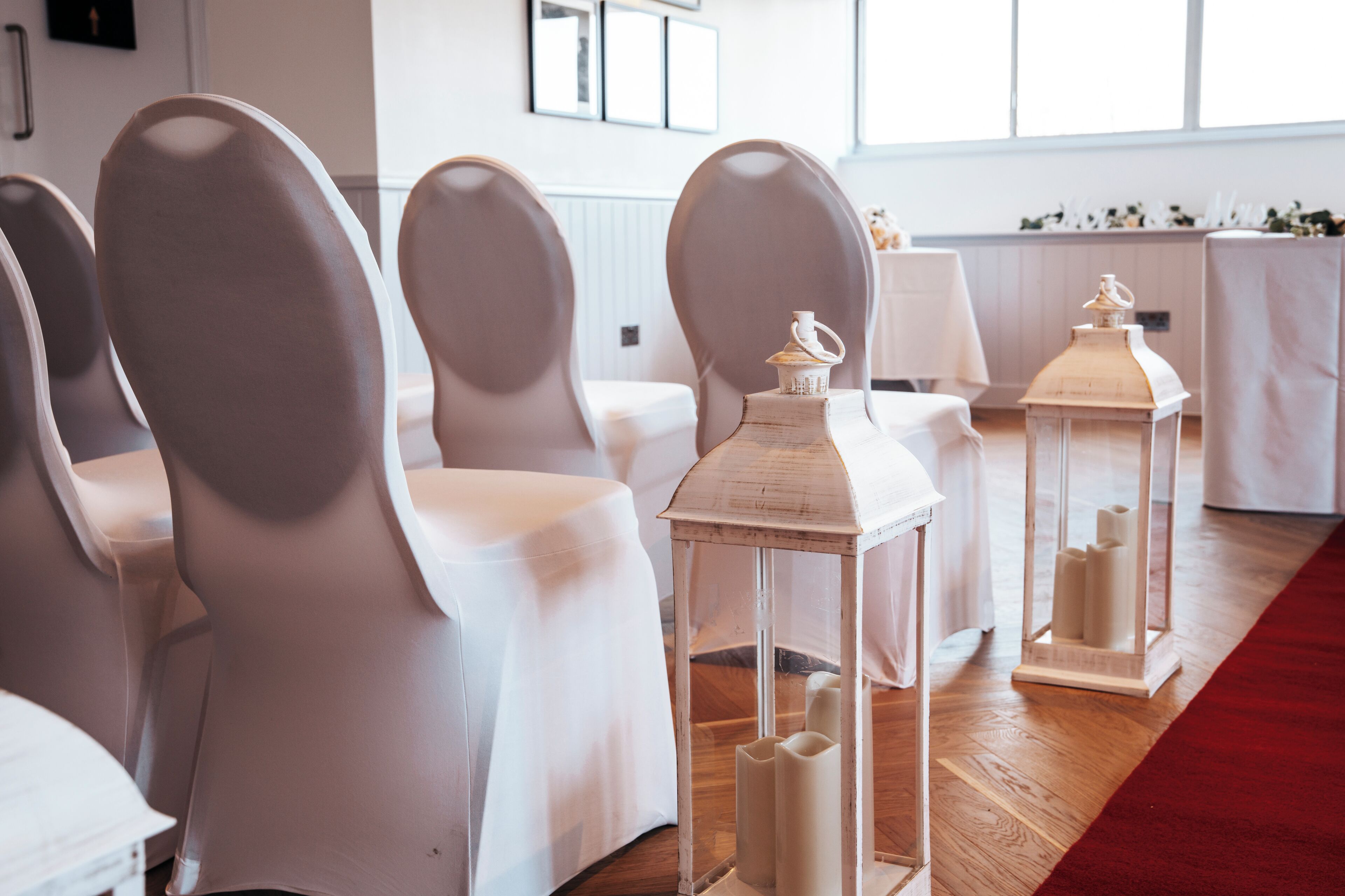 Une pièce avec des chaises et des tables blanches, une moquette rouge et des lanternes décoratives.