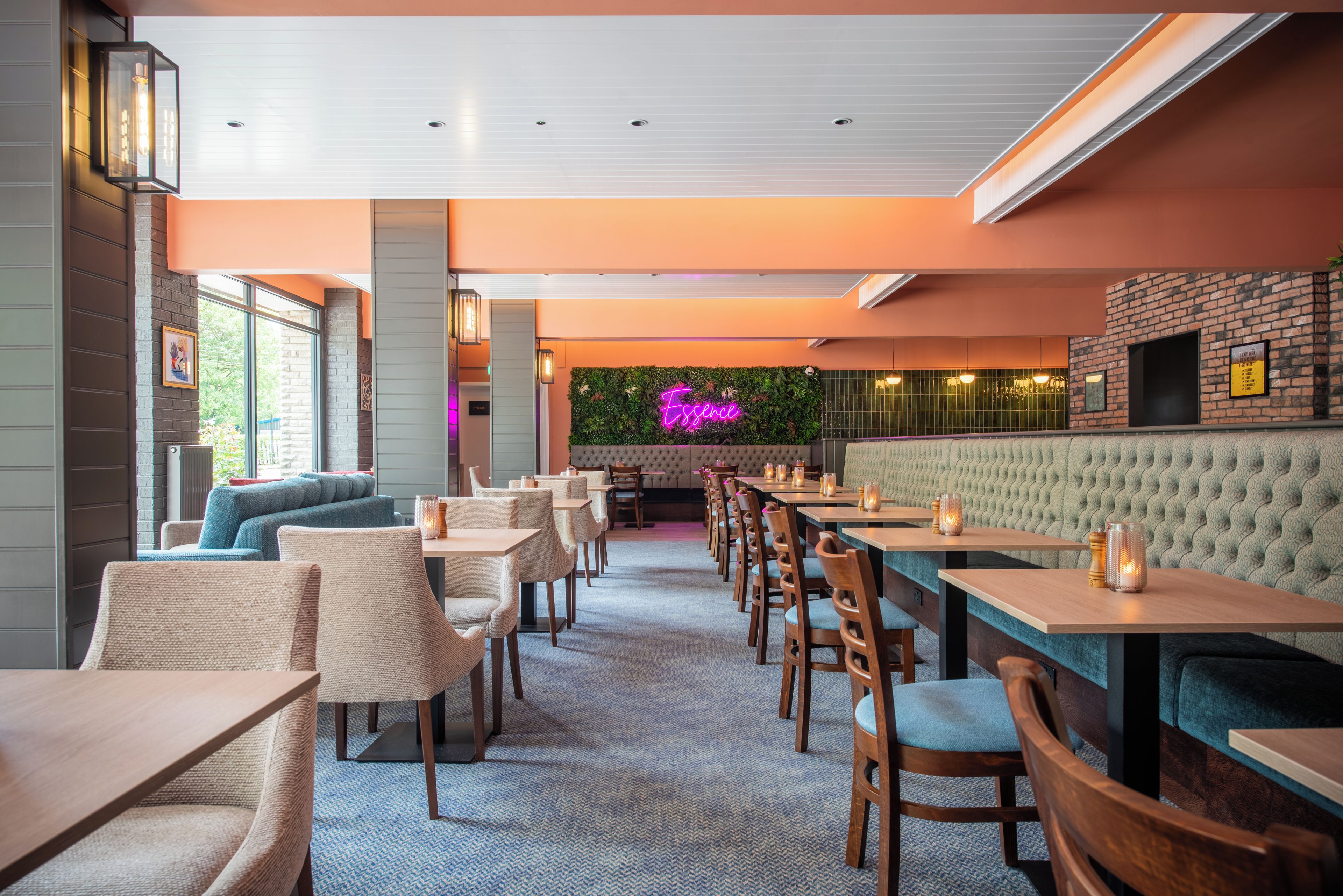 A restaurant with a long counter, cushioned seating, and a neon sign.