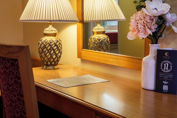 Una recepción de hotel con dos lámparas, un florero con flores y una tarjeta promocional.
