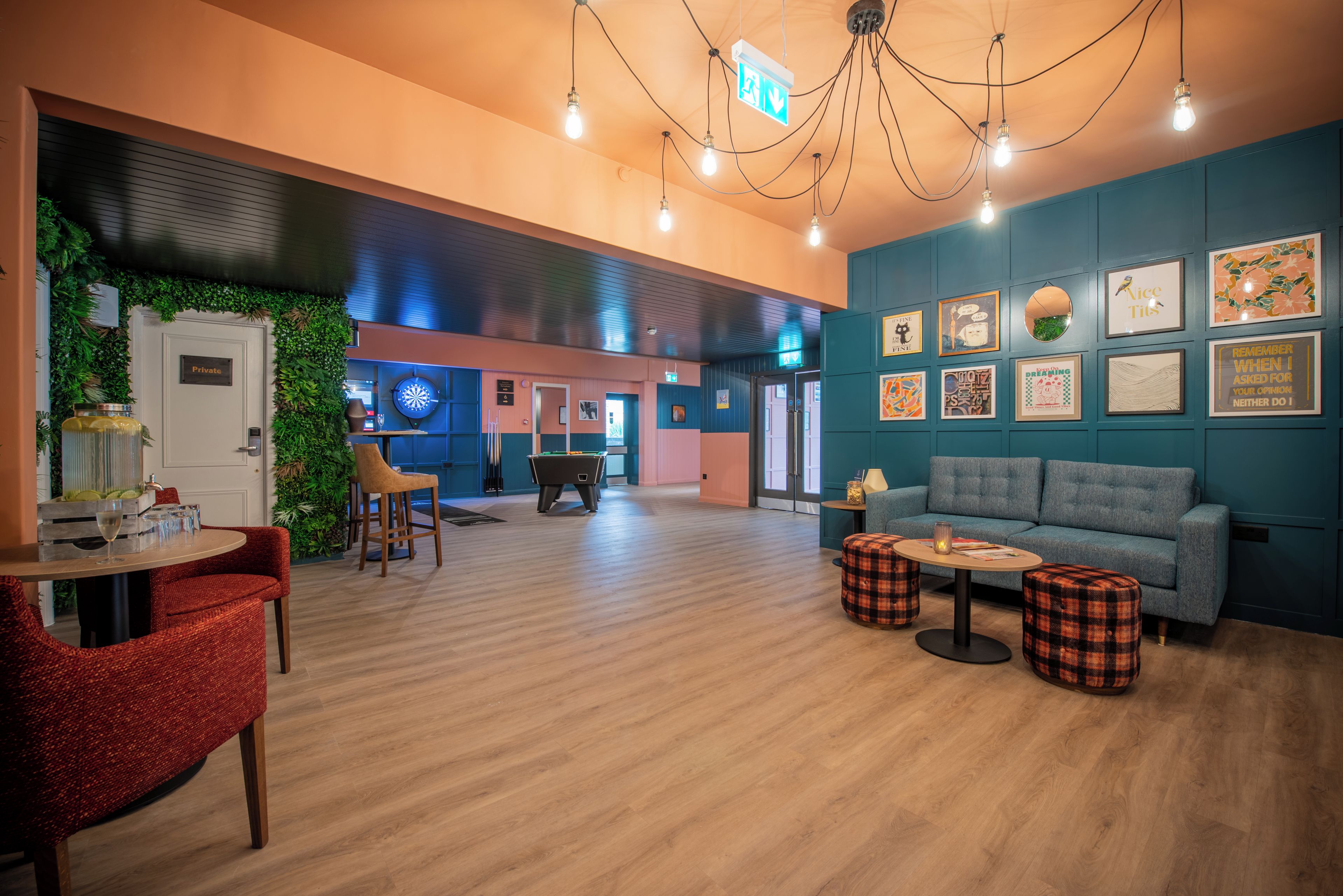 Un espace de détente moderne comprenant une table de billard, des sièges et un mur décoré de divers tableaux encadrés.