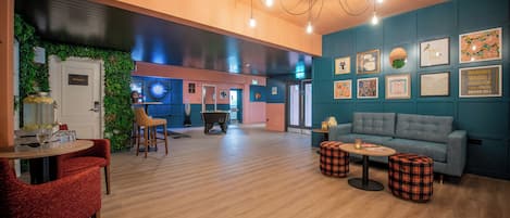 Un espace de détente moderne comprenant une table de billard, des sièges et un mur décoré de divers tableaux encadrés.