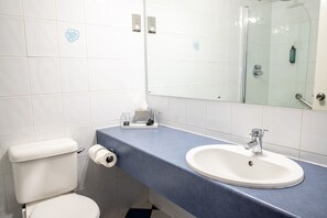 A bathroom with a white toilet, a sink with a blue countertop, and a mirror. - Tiverton Hotel Lounge & Venue (Tiverton)
