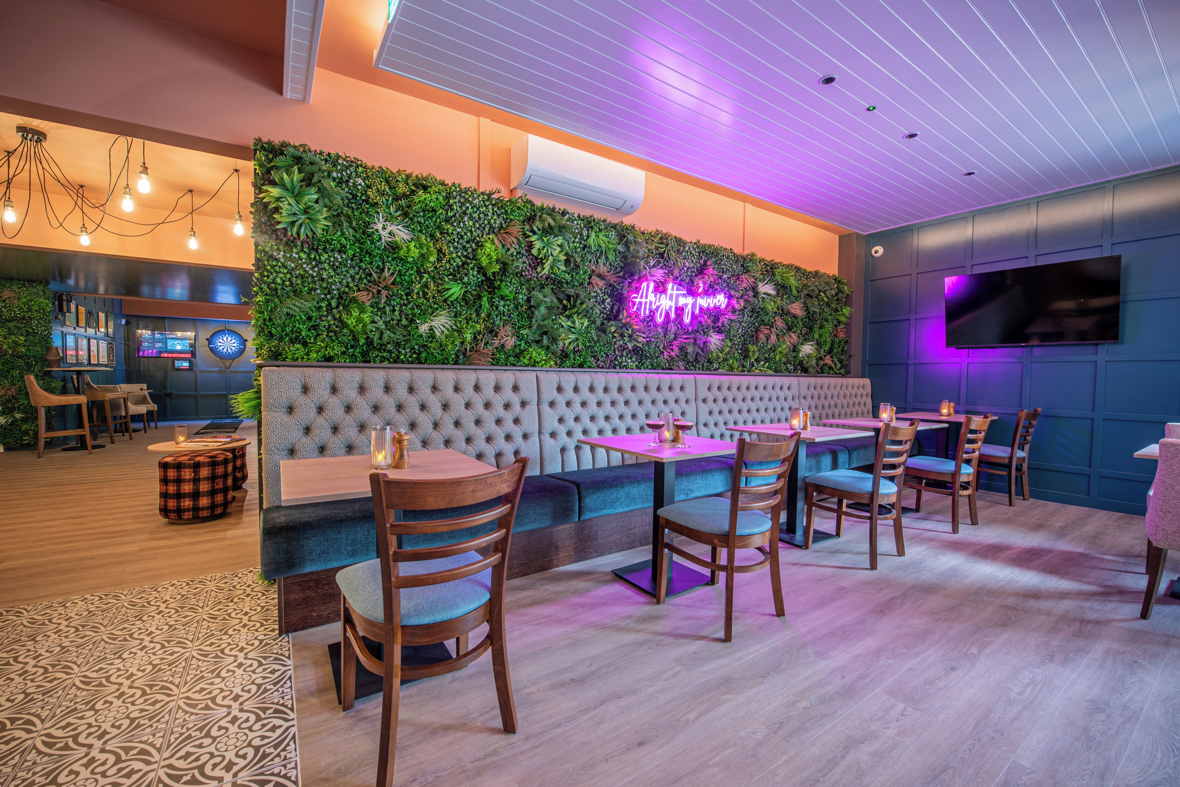 A modern lounge area with a green wall, seating, and a neon sign.
