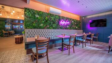 A modern lounge area with a green wall, seating, and a neon sign.