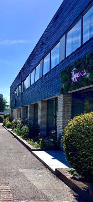 Een gebouw met een bakstenen gevel, grote ramen en een neonreclame.