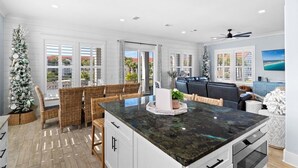 Une cuisine moderne dotée d’un grand îlot central, de meubles blancs et offrant une vue sur l’extérieur.