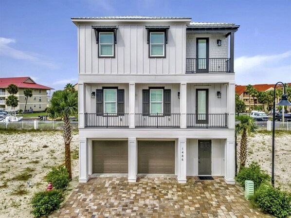 A two-story building with a garage at the ground level and a balcony on the upper floor.