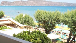 A beach with umbrellas and lounge chairs, a pool area, and a view of the sea and mountains. - Kato Stalos Beach (Chania)