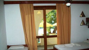 A room with two beds, a sliding glass door leading to an outdoor area with umbrellas. - Kato Stalos Beach (Chania)