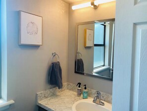 Une salle de bain avec un comptoir en marbre, un lavabo, un miroir et un porte-serviettes.