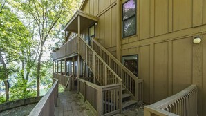 Eine Holzterrasse mit einer Treppe, die zu einem Balkon im zweiten Stock führt.