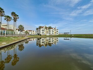 Hotel à beira-mar com várias varandas, um lago refletor e palmeiras.