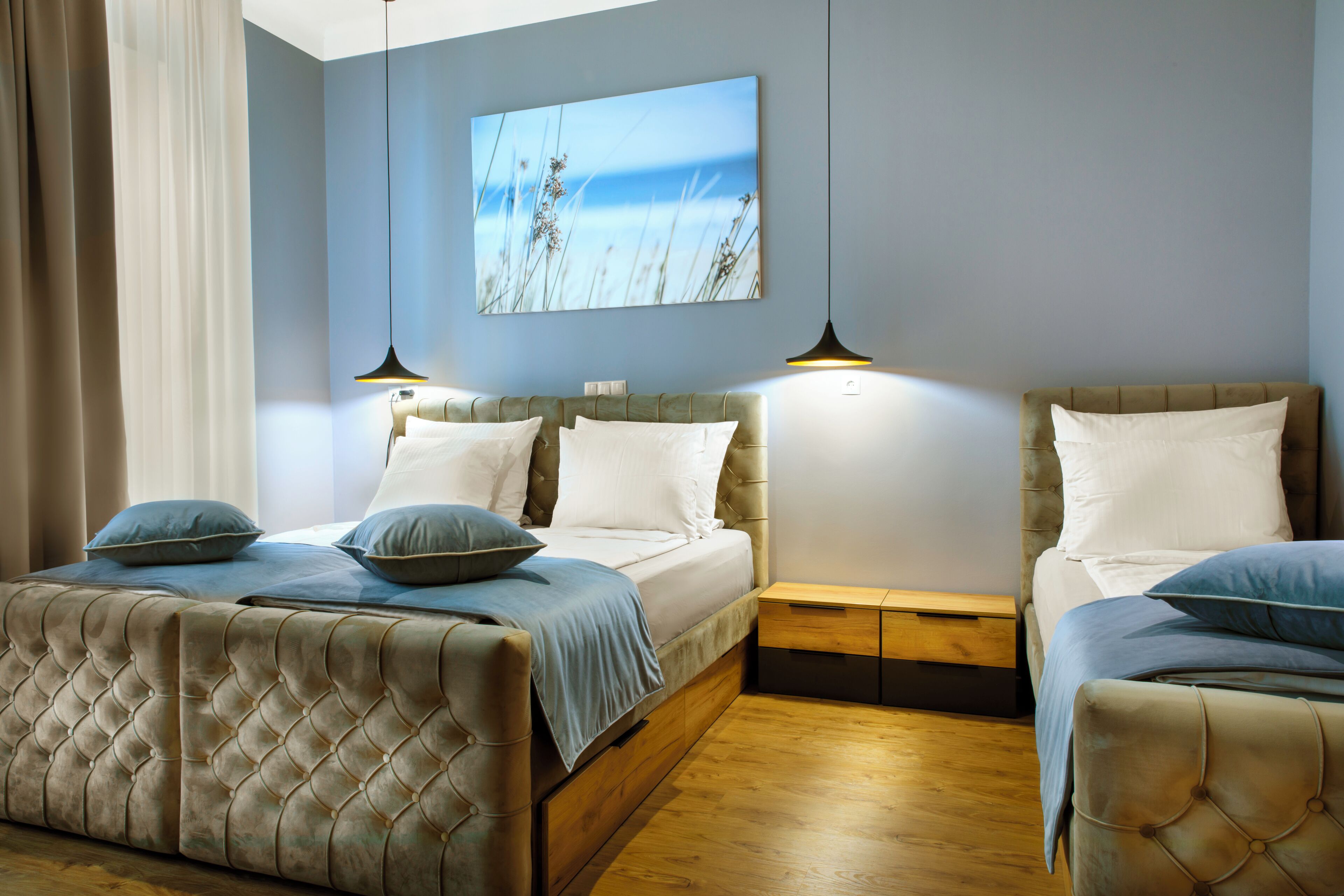 Camera da letto con due letti, un comodino in legno, una tavola da notte e un quadro appeso al muro.