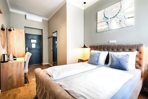 Una camera d'albergo con un letto, comodini, una scrivania, una sedia e una porta.