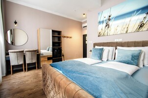 Quarto com cama grande, guarda-roupa, espelho e secretária com cadeiras.