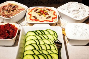 Uma mesa com diversos pratos de comida, incluindo uma salada de pepino, um molho de tomate e um prato cremoso branco.