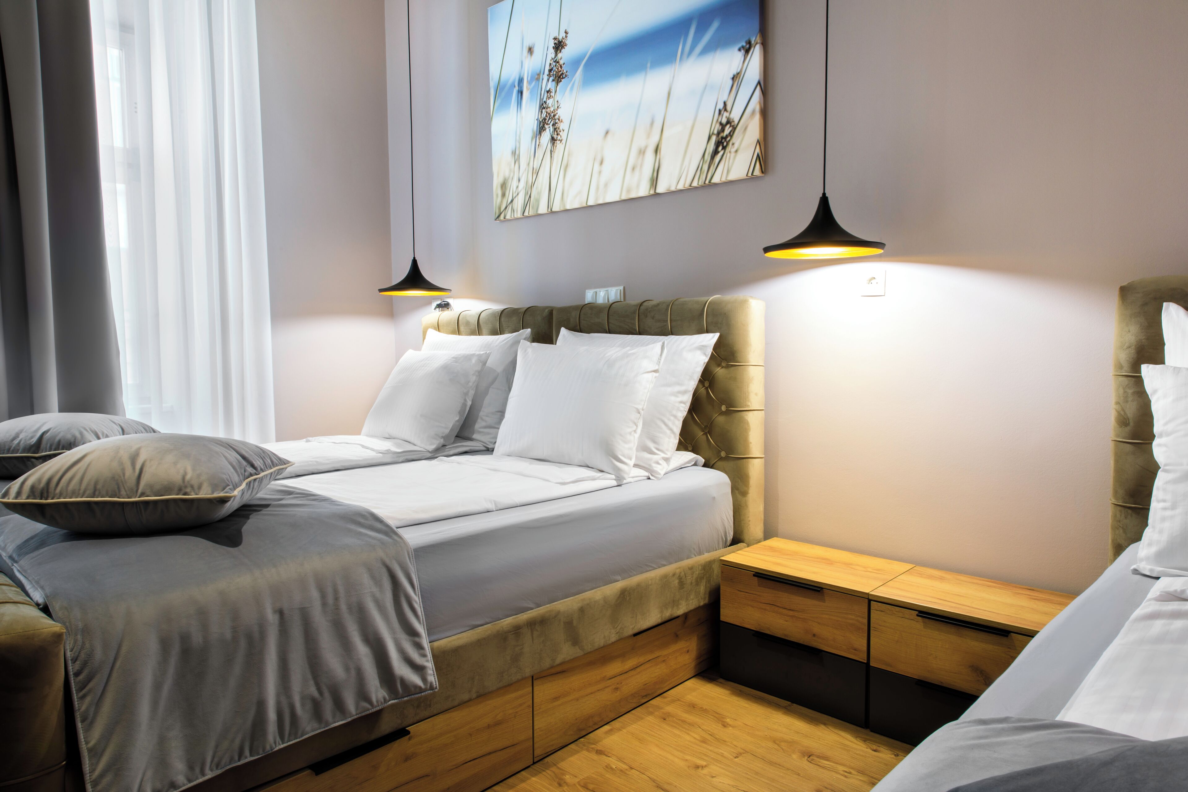 A modern bedroom with a bed, bedside tables, and a wall-mounted artwork.