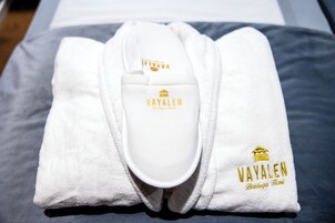 Um roupão branco dobrado com o logotipo VAYALEN e a inscrição 