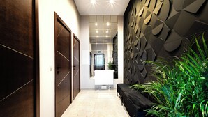 A modern hallway with a bench, a plant, and a wall with geometric patterns. - Vayalen Boutiquehotel  (Vienna)
