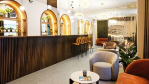 A modern hotel lobby with a reception desk, seating area, and decorative plants. - Vayalen Boutiquehotel  (Vienna)