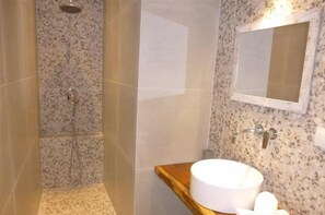 A bathroom with a shower, a sink, and a mirror.