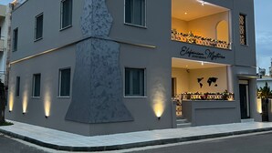 Ein modernes, zweistöckiges Gebäude mit einer markanten Fassade, mit dem Schriftzug 'Eleftherian Mysteries Apartments'.