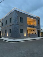 A modern two-story building with a unique facade, labeled "Eleftherian Mysteries Apartments."