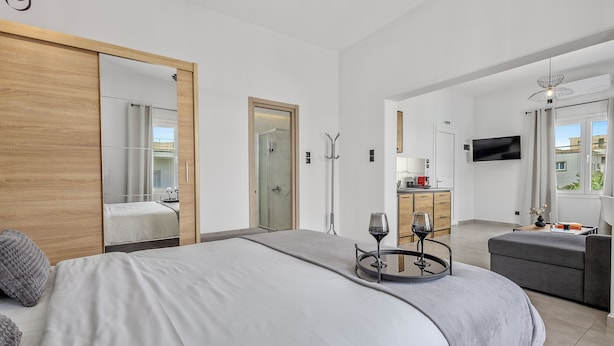 Ein modernes Hotelzimmer mit einem großen Bett, einer Sitzecke, einem Fernseher und Blick ins Freie.
