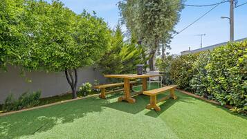 Une terrasse avec un revêtement de gazon synthétique, des tables en bois et des bancs.